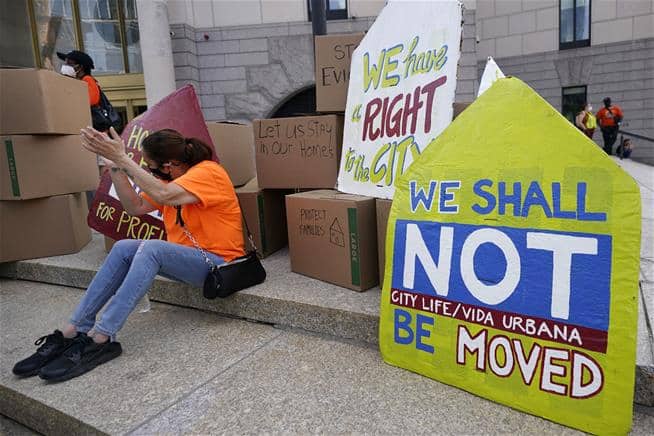 A woman applauds a speaker during a June rally in Boston protesting housing evictions. (AP Photo/Elise Amendola)